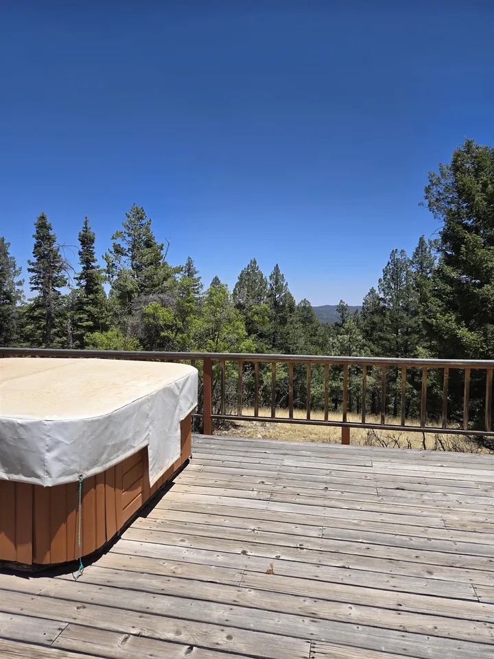 Corner of the deck with the covered hot tub at left, looking out over the treetops toward distant mountain ridges